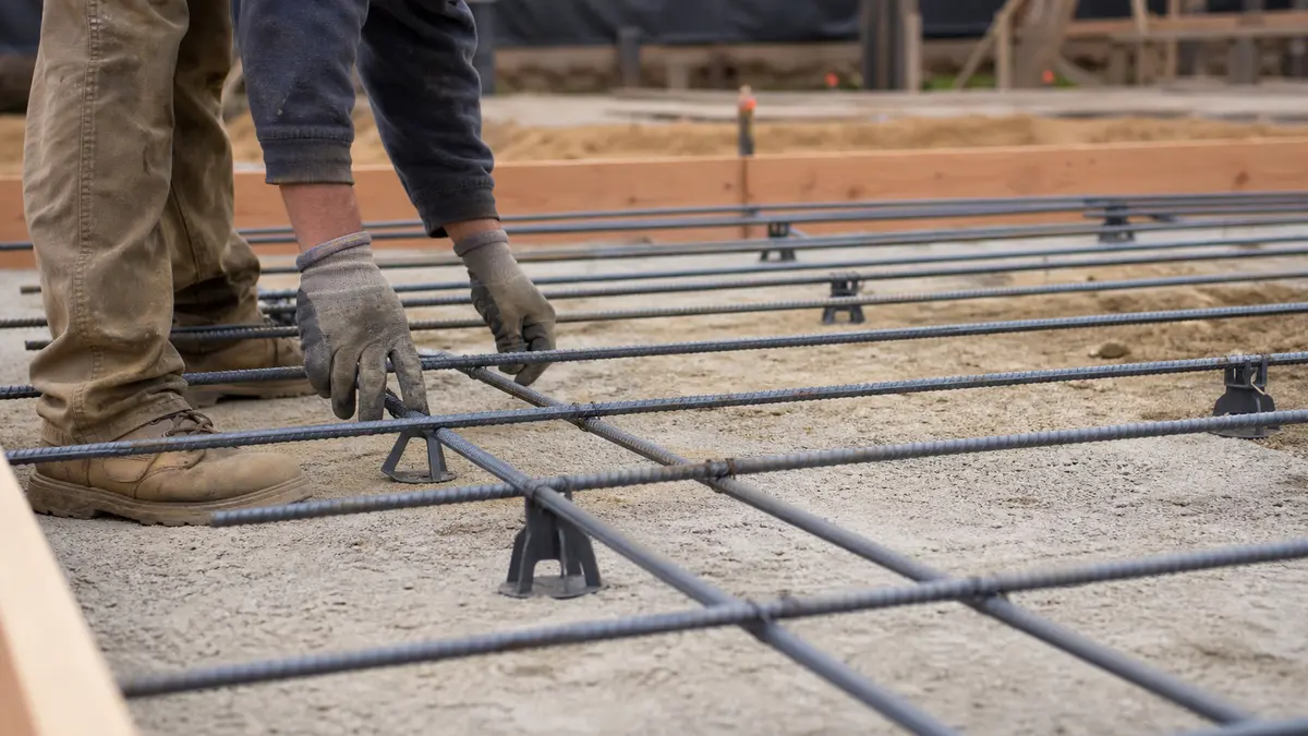Worker setting a number 3 rebar grid on chairs before a concrete slab pour